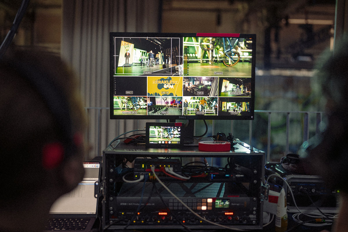 Technikai kontrollterem több képernyővel és hangmérnökkel élő esemény közvetítése, livestream produkció működés közben.
